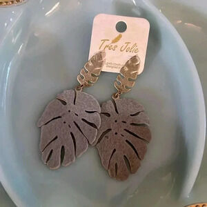 Tres Jolie monstera leaf plant earrings gold look with gray felt overlay.